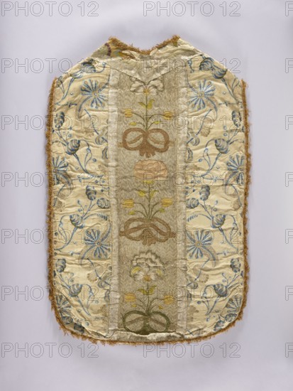 Chasuble. Chasuble with a column embroidered with colored silk with large, convex flowers on a silver background. Sides of white brocaded silk with navy blue flowers and gold. England, 1740s. The background of the embroidered column is worked in silver threads and stitched in horizontal zigzags with cotton thread; on this background is embroidery in colored silks—flat and gold thread—laid in motifs of floral bouquets tied with a ribbon. Bouquets of three flowers each: two small tulips symmetrically and a large blooming peony. Colors: yellow, green, pink, and blue. Trimmed with gold threads. The columns are edged with silver braid with a scalloped pattern. A fabric gap at the neck is filled with a fragment of embroidered silk grosgrain in a similar color a fragment of a large pattern indicates it may be from a tapestry. Linen lining. Gold embroidery in a flat laid stitch. Metal threads, a silver and gold plate woven on a rather thick linen yarn. Metal threads twisted with colored silk t...