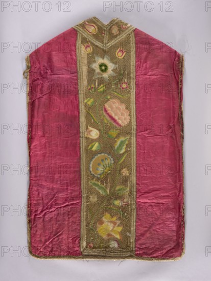 Chasuble, Liturgical vestment, 1797, Poland. The back features a column embroidered with colorful silks of large flowers on a gold background; the sides are amaranth silk taffeta and the front sides red taffeta. The columns are embroidered on a gold background in zigzag twig patterns with large stylized flowers. Trimmed with silver braid in a diamond pattern with gold stripes. Cotton lining. Dimensions: length 114 cm, width 73 cm back., A textile panel with a central decorative vertical band flanked by two large pink panels; the pink areas are slightly wrinkled and show variations of lighter and darker pink. The central band has a gold background with embroidered floral motifs in colors including green, yellow, blue, white, and pink, and includes leaves and stylized blossoms. The top of the textile forms a pointed shape and the edges are trimmed with a frayed gold border. The surface shows signs of wear and some loose threads.