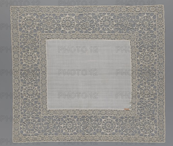 Doily, geometric ornaments, rosettes ornament, doily with smooth center. Edge made of white linen lace with rosette motifs: large rosettes in the center and rows of small rosettes on the edges; punto in tela lace; ca. 1600, Italy. Materials: lace, fabric. Dimensions: height 79 cm, width 70 cm., A square fabric piece with a plain central panel in light gray surrounded by an ornate openwork lace border in off-white and cream tones, the lace forming repeating circular and floral motifs and interconnected geometric patterns, all set against a medium gray background.