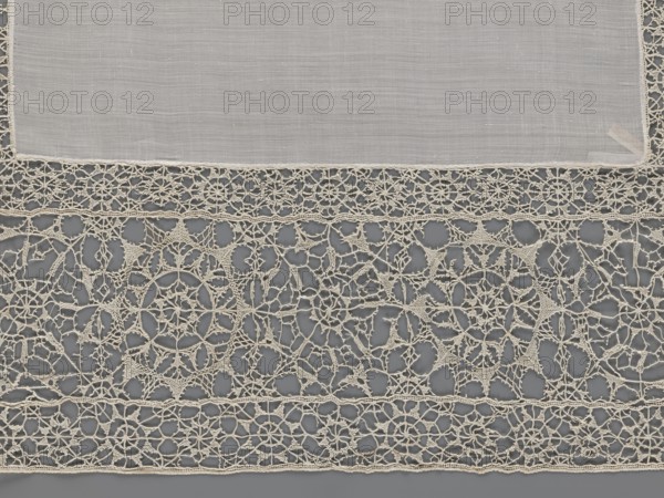 Doily, geometric ornaments, rosettes ornament, doily with smooth center. Edge made of white linen lace with rosette motifs: large rosettes in the center and rows of small rosettes on the edges, punto in tela lace, ca. 1600, Italy, lace, fabric, height 79 cm, width 70 cm, A rectangular piece of translucent fabric in a pale off-white color lies across the top of the image, edged with a delicate decorative border of the same color; below it a wide section of intricate openwork lace in an off-white or cream color fills the lower area, featuring repeating circular and star-like motifs connected by fine looping threads and small triangular mesh accents, set against a smooth muted gray background that shows through the lace openings.