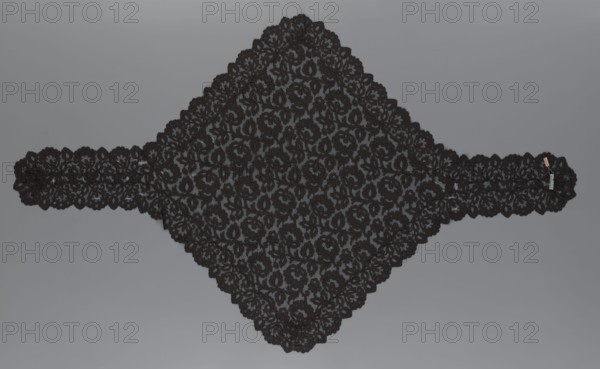 Cape, lace, in the form of a square with two wide, elongated lace ties. Continuous floral ornament with a motif of a large, asymmetrical flower sprig. Raised edge, a strip of floral edge ornament made separately and sewn on. 2nd half of the 19th century, France. Height 97 cm, width 168 cm., A large triangular piece of black lace with an intricate floral pattern lies flat against a neutral gray background, extending into a narrow band on each side; the lace has scalloped edges and repeating flower and leaf motifs, with the black lace appearing slightly raised against the gray, and a small neutral-colored tag attached near one end.