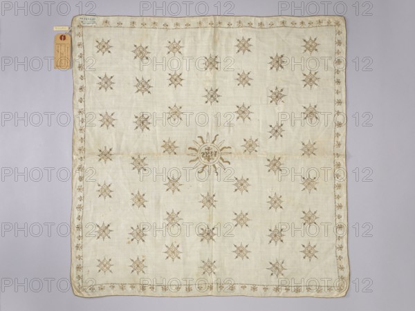 Velum made of white linen fabric with a rare plain weave 25 warp threads and 30 weft threads per 1 cm. Embroidered with gold thread on a silk backing with pierced stitches. Double-sided embroidery, equally careful on the right and left sides. Metal thread woven on thick silk thread. In the center, in a radial circle, the IHS monogram with a cross. In the field of the napkin, radial rosettes arranged in 6 rows, 7 in each, offset. Small stylized ornaments flower branches? in the border. Liturgical vestment, 16th/17th century, Poland. Height 66.5 cm, width 65 cm., A rectangular light beige cloth with a pale lavender-gray background, decorated all over with a repeating motif of small stylized sun-like shapes in a muted brown color and a larger central sun motif in the same brown; the cloth has a narrow decorative border of similar brown motifs and a sewn edge, with a small brown paper tag attached near one corner.