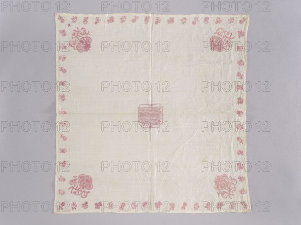 Velum, church paraments, Henryków German: Heinrichau. Flowers, leaves, plant ornaments; sacred art; churches and chapels furnishings. Velum made of white linen batiste. In the center, in a cartouche, an embroidered inscription in German and the date 1700. Border of small floral sprigs, with one large floral sprig in each corner. In one corner, a small monogram EN under a crown. Color of the ornament light raspberry. Flat, pierced, double-sided embroidery. Stitches: satin, cord, split, cross. Letters and numbers are made with crosses, each cross on three warp threads and three weft threads. 1700, Silesia. Liturgical vestment. Height 77 cm, width 75 cm., A square cloth laid flat on a light gray surface, mostly off-white in color with a visible central vertical and horizontal fold, featuring a delicate border of small floral motifs in pink along all edges and larger pink floral corner designs in three corners, with a pink decorative motif near the center; the fabric shows slight wrinkles ...