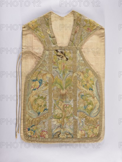 Chasuble, provenance, birds, flowers ornament, fruit ornament; liturgical vestment; plant ornaments; church paraments; sacred art; Embroidered chasuble. On a silver background, a multicolored pattern composed of a fruit vase, floral scrolls, grapes, and birds. Predominant colors: silver background and green, blue, and yellow ornament. Edges trimmed with gold braid with a geometric pattern. Internal divisions marked with strips embroidered with gold thread, imitating haberdashery. Cotton lining. Embroidery on linen canvas with multicolored silk and metal threads in two colors: silver silver plate woven on a white silk base and gold gold plate woven on a yellow silk base. Metal thread embroidery in a laid flat stitch; colored embroidery in split, flat, and knot stitches. E. Soszko; 18th century, Poland. Liturgical vestment. Length 105 cm, width 64 cm back., A textile vestment with a light beige background and ornate embroidered panels in muted gold, green, blue, pink, and cream tones, fe...