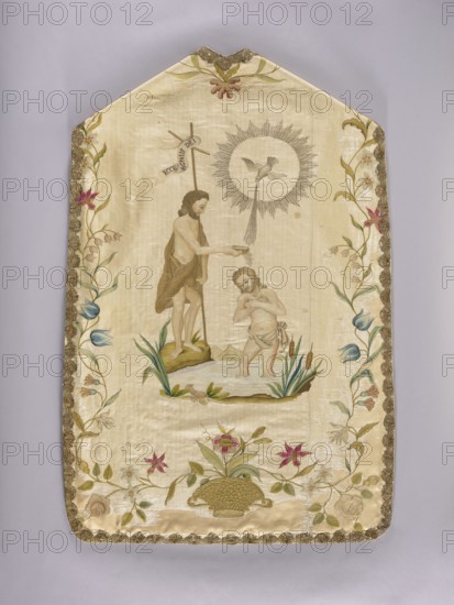 Chasuble, 18th century, Poland. Cream silk grosgrain with cotton lining and thick canvas backing; lined with linen canvas. Embroidery in silk thread and metal-braid thread using shaded chain stitch; edges trimmed with bobbin lace and gold lace. Front center: embroidered lamb lying on a book from which seven seals emerge, surrounded by clouds; delicate floral tendril around the edges; basket of flowers at bottom edge with a long floral tendril. Back: John the Baptist baptizing Christ, above them a dove in a radial rim; John holds a cross bearing a ribbon inscribed ECCE AGNUS DEI. Pastel colors. Function: liturgical vestment. Dimensions: length 113 cm, width 69 cm back., A vertical, cream-colored textile panel with a pointed top and scalloped gold trim along the edges, featuring an embroidered central scene of two male figures by a small body of water with green grassy tufts and brown cattails; one figure stands on a green patch holding a long staff and is draped in a brown garment, whil...