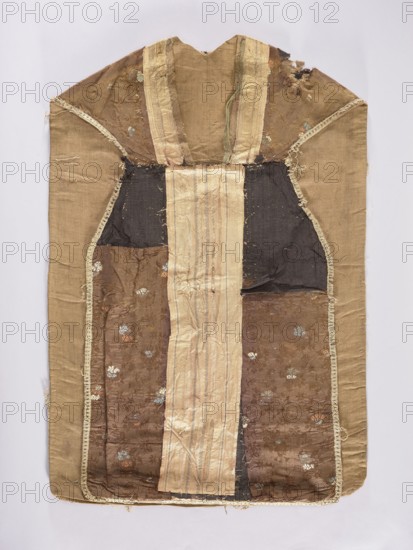 Chasuble, unknown creator; liturgical vestment, 18th century. Silk columns with a pattern of pink and silver stripes. Sides made of brown fabric with floral motifs, partly in damask technique and partly brocaded with colorful silks: sky blue, pink, and cream. Flowers and plant ornaments; sacred art; churches and chapels furnishings. Place of origin: France columns, Venice sides. Length 112 cm, width 70 cm back., A flat textile panel with a worn, patchwork appearance showing a central vertical pale beige stripe flanked by darker brown and black fabric panels, framed by faded tan-beige outer panels and edging; the brown areas display a subtle floral brocade pattern with small floral motifs in muted blue, white, and rust colors, and the fabrics show fraying, seams, and areas of wear and thinning, especially near the top where there are irregular torn sections; narrow decorative trim in a light beige runs along some inner seams, and the overall palette includes tan, beige, brown, black, mu...