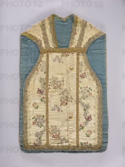 Chasuble, floral ornaments with flowers and leaves; columns on the back highlighted with wide gold braid; blue linen lining; 18th century, Lyon; liturgical vestment/parament; length 107 cm, width 67 cm back., A garment-shaped textile with a central panel of cream silk patterned with floral embroidery in shades of pink, red, green, purple, and yellow, bordered by narrow bands of gold trim and wider panels of pale blue silk at the sides and top; the cream sections show scalloped gold lace edging and a few areas of wear and fraying, while the pale blue fabric appears smooth with some creasing; overall the piece has a symmetrical, tapered shape with curved side seams and a rounded bottom edge, and the visible colors include cream, pale blue, gold, pink, red, green, purple, and yellow.