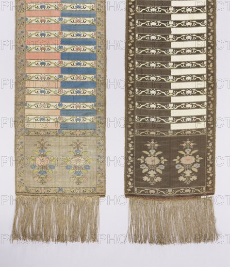 Kontusz sash. Semi-solid, four-sided sash with plant and flower-bush ornament; bipartite heads with a motif of a stylised flower tree growing from a miniature mound. One side: white and brown background with brown heads; other side: blue, crimson and gold heads. Pattern on the gold heads is multicolored; on the brown heads is off-white. Signed at the bottom of the heads, lying down, FS. 18th century, Lyon. Polish sash used with national costume; men's fashion accessory. Length 294 cm, width 30 cm., Two long vertical woven panels hang side by side against a pale background. The left panel has a light beige ground with horizontal bands of alternating pastel pink and blue, narrow decorative floral bands in green and cream, a lower section featuring stylized bouquets in pale pink, blue, yellow, and green, and a fringed bottom of golden threads. The right panel has a darker brown background with similar horizontal striped sections in cream and brown, decorative floral bands in cream and gre...