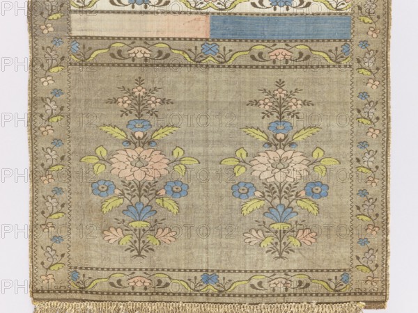 Kontusz sash, semi-solid sash with flower bushes ornament, four-sided sash with plant ornaments, Polish sash used in national costume, men's clothing accessory. Bipartite heads with a motif of a stylised flower tree growing from a miniature mound: on one side a white and brown background with brown heads, on the other blue and crimson and gold heads. The pattern on the gold heads is multicolored, and on the brown heads is off-white. Signed at the bottom of the heads, lying down, FS. 18th century, Lyon. Length 294 cm, width 30 cm., A rectangular woven textile with a muted beige background featuring a repeating floral motif in pastel colors; a pair of vertical floral sprays with stylized blossoms in pale pink and blue, leaves in light green, and outlining in brown sit side by side within a bordered field, accompanied by smaller floral clusters above; a decorative inner border with flowing vine shapes and small flowers in blue, pink, and green surrounds the central area, and a narrow oute...