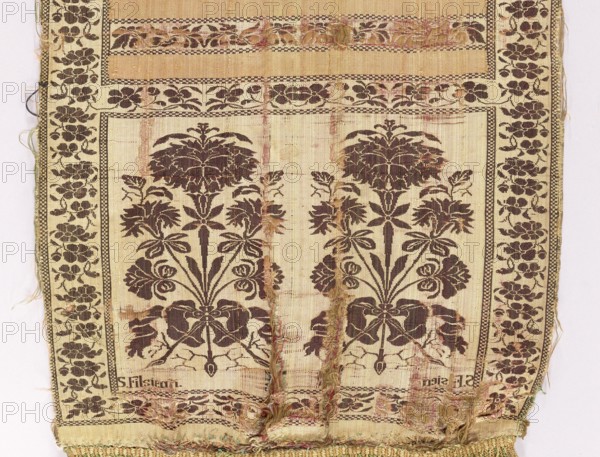 Kontusz sash, Szczepan Filsjean Manufactory Kobylka; belt manufacturer; 1787–1794. Silk kontusz sash, double-sided. Bipartite heads with bouquets of flowers carnations rooted and tied with ribbon; alternating smooth stripes and floral twigs. Trimming with floral twig. Colors: brown, cream, olive and crimson. Sew-on silk fringe in green, straw and ochre. Ornament: - Heads: two floral bouquet motifs each. - Middle: alternating transverse shelves, plain and with a floral tendril motif. - Borders: vertical and horizontal with a tendril motif, as in the shelves; checkerboard. Colors detail: - Principal: cream-pink background of heads, borders and shelves with tendril, brown ornament; plain crimson-pink shelves. - Reverse: right, except for plain green shelves. Signed in the corners of one of the heads, under the main motifs: S. Filsjean. Weave density: approx. 17/48 x2. Place/date: Kobylka, Poland, 1787–1794. Type: clothing accessory, national costume. Dimensions: length 342 cm, width 28.5 ...