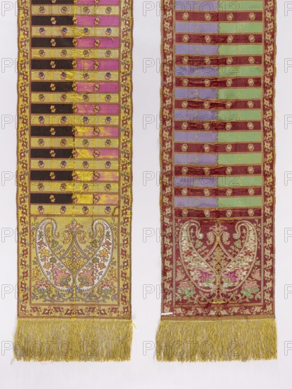 Kontusz belt, gift; bota ornament; Polish costumes; kontusz belts, sashes. Four-sided belt decorated with heads with two bota palmettes in a symmetrical, mirror-like arrangement filled with fine ornament. Stripes with a pattern of small floral projections resembling pansies, alternating with smooth shelves; borders of plant tendrils. Colors — right side: golden brown, plum background, and silver, blue, and green ornament; left side: green brown and sapphire background, and gold, green, and plum ornament. Right side: background of the heads, the border, and every other shelf are gold, with silver, blue, green, magenta, yellow, and brown ornament; remaining shelves half brown and half magenta. Left side: background of the heads, the edges, and the shelf are brown; remaining shelves half purple, half green; gold ornament as on the right. Gold fringe sewn on. 2nd half of the 19th century, Poland, Moravia ; clothing accessory. Length 344 cm; width 30.5 cm., Two long vertical textile panels ...