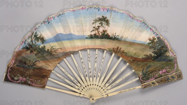 Fan, Fan painted from carved ivory. Feathers decorated with gold and silver metal foil and sequins. Cover feathers with openwork decoration featuring a motif of ovals, shells, and floral sprigs. The right side of the cover is painted in gouache with a pastoral scene in a park landscape, rendered in whitened colors with dominant blues sky/background and pinks architectural elements and figures' clothing. The left side of the cover shows a landscape with mountains in the background. The scenes are framed by a delicate gold-painted Rococo ornament. Pastoral scenes, landscapes, plant ornaments; fashion accessory. 2nd half of the 19th century; possibly 18th century; France/Europe. Height 27 cm. Provenance unknown., A decorative hand fan with a painted landscape on its leaf, showing a horizon with a pale blue sky fading to a light creamy tone above a muted green and brown foreground, featuring a few trees and shrubs with green and reddish foliage and small clusters of flowers, framed by a de...