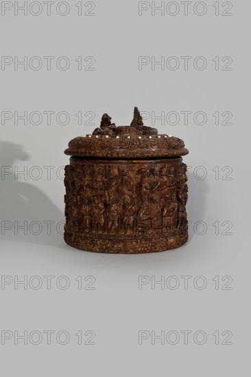 Wooden tankard, carved, probably a peg tankard, maker, religious scenes, Gospel scenes, Resurrection of Christ iconography; inscriptions; vessels; Passion Bible; New Testament; human figures; figurative motifs; ; decorative art. Wooden pear-shaped tankard, so-called peg tankard, round, richly decorated with bas-reliefs depicting Passion scenes, with a Resurrection scene on the lid. The lid rim and handle are decorated with plant motifs and masks, and studded with ivory pins. In the center is a row of vertically driven metal pegs placed at regular intervals the top two are missing. 17th century, Scandinavia; vessel. Height 23.5 cm, width 20.5 cm., A carved cylindrical container with a lid sits against a light gray background, the container rendered in rich brown tones with darker and lighter brown variations; the lid is topped by sculpted protrusions and a ring of small pale bead-like elements, and the body is covered in detailed low-relief carved figures and decorative motifs, casting ...
