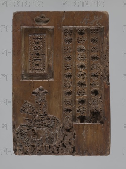 Double-sided gingerbread mould. One obverse: genre scene of a man standing by a washtub washing, behind him a woman holding a baby in swaddling clothes; below a plaque with an inscription in German; made in Schwabach. Reverse: three motifs — bottom left, a rider in a hat on a horse; above him a rectangular recess containing a second rectangle with the letters I and B carved, surrounded by geometric and plant ornaments; right side, a tripartite rectangular recess with a vertical strip of floral decoration in each segment; above it carved initials A and H. Materials: gingerbread mould wood. Iconography: genre scenes, babies, children, rider on a horse, floral motifs, plant motifs, social satire. Date: 18th–19th century. Place: Province of Silesia 1742–1918. Form dimensions: rectangular; height 24.7 cm, width 16.8 cm, depth 4.2 cm., A rectangular carved wooden panel with a brown surface shows a carved scene and decorative patterns; on the left a framed recessed panel sits above a carved f...