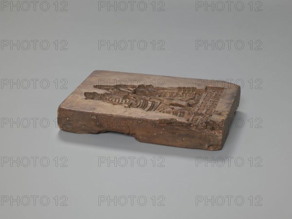 Double-sided gingerbread mould. Oblong rectangular mould, Schwabach, 18th–19th century, Silesia Province of Silesia, 1742–1918. Height 24.7 cm, width 16.8 cm, depth 4.2 cm. Obverse: genre scene — a man standing by a washtub engaged in washing; behind him a woman holds a baby in swaddling clothes; below a plaque with an inscription in German. Reverse: three motifs — bottom left, a rider in a hat on a horse; above him a rectangular recess containing a second rectangle carved with the letters I and B, surrounded by geometric and plant ornaments; right side, another tripartite rectangular recess with a vertical strip of floral decoration in each segment; above it carved initials A and H. Subjects/themes: genre scenes, babies/children, riders, floral and plant motifs, decorative/applied art, gingerbread mould, social satire;, A rectangular wooden block with carved recessed designs rests on a smooth flat surface; the block shows a worn, uneven top with detailed relief carvings and rough, chi...