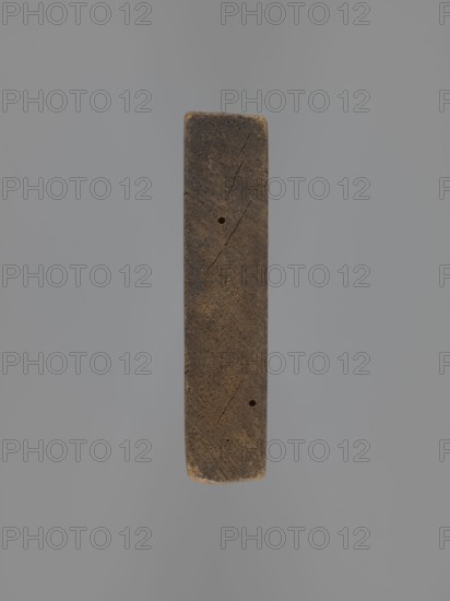 Double-sided gingerbread mould with the image of a rider on both sides, maker, gingerbread; wood; folk-style plant decorations; military uniforms; sabres; hussars; horse rider iconography; rectangular double-sided mould. One side: rider in a military uniform decorated with braiding, likely hussar formation, wearing a high mirliton-type headgear, holding a sabre; plant decoration at the bottom. Other side: rider in a different military uniform, wearing a cap with a feather, holding a pole weapon lance or lance with a sabre at his side; horse's head dressed with decorative covering; decorative plant motifs at the bottom. 18th–19th century; Silesia Province of Silesia, 1742–1918. Form; height 17.2 cm, width 9 cm, depth 2 cm., A vertical rectangular object with rounded short ends, appearing textured and worn, suspended against a plain background; the object is primarily brown with darker brown areas and small lighter brown spots, showing surface cracks and two small round holes; the backgr...