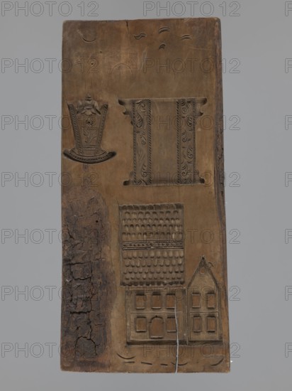 Double-sided gingerbread mould. Obverse: figure of a bearded man in patterned clothes, richly decorated with geometric motifs, wearing a hat with a feather and blowing a horn French horn; plant ornament at the bottom. Reverse: several small elements including houses with tiled roofs, a cradle decorated with a flower motif, and a chest or bed decorated with a plant twig. Folk-style decorations, figurative scenes; geometric and plant ornaments; male figure; applied/decorative art. Double-sided rectangular form. 18th–19th century, Silesia Province, 1742–1918. Height 30 cm, width 13.8 cm, depth 2 cm., A vertical wooden panel with carved depressions showing a variety of decorative motifs and architectural forms, the wood ranging from medium brown to darker brown patches and a strip of rough, cracked dark brown bark along one side; near the top a carved band with ornate vertical panels and scrolling leaf patterns sits beside a shallow curved floral motif, while below there is a carved rectan...