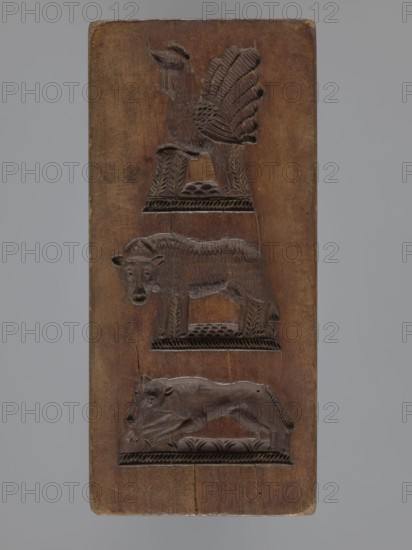 Double-sided gingerbread form with three representations on both sides;, Rectangular form, height 16.7 cm, width 7.7 cm, depth 3.2 cm. One side: three vertically arranged animals—a rooster, an ox, and a dog—set on bases and decorated with geometric and floral motifs. Other side: three images—a guitar, a stork, and a rider on a horse blowing a horn and wearing a bicorn—each decorated with geometric-floral ornament. Zoomorphic and figural motifs; decorative folk motifs. Gingerbread mold, 18th–19th century, Silesia Province of Silesia, 1742–1918., A vertically oriented rectangular wooden panel with a brown surface features three carved animal reliefs stacked vertically; the top relief shows a bird with a raised tail and carved feather details standing on a decorated platform, the middle relief depicts a standing hoofed animal with a head turned slightly forward on a similar decorated base, and the bottom relief shows a reclining or crouching animal with a long body and visible limbs on a ...
