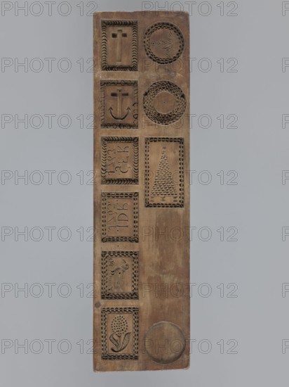 Double-sided gingerbread mould. Obverse: images of four heads; depending on rotation the faces appear male or female in one, the male head changes into a goat. Reverse: seven elements in decorative frames: a house roof, a flower, a bird, a plate inscribed IDR / 1763 and another inscribed GFK / 1763, an anchor and cross, and a medallion with wreath and flower motif. Materials: applied art, folk art; motifs include plant ornaments, human figures, zoomorphic motifs, wreaths, religious symbols, inscriptions, customs, souvenirs. Date: 1793 with inscriptions dated 1763. Region: Province of Silesia 1742–1918. Form: double-sided mould. Dimensions: height 34.6 cm, width 9.3 cm, depth 2 cm., A long rectangular wooden panel with a vertical arrangement of carved rectangular and circular recessed panels, the wood showing brown tones with lighter and darker variations, several rectangular frames containing carved motifs including crosses, a curved anchor-like shape, a triangular tree-like pattern, a...