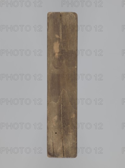 Double-sided gingerbread mold; obverse: baby in swaddling; reverse: baby in swaddling. Folk-style decorations with geometric and floral ornament; decorative frame around the figure. Applied art, souvenirs; gingerbread mold. Rectangular shape. 18th–19th century. Province of Silesia 1742–1918. Mold. Height 16.8 cm, width 7.8 cm, depth 3.7 cm., A long rectangular wooden plank viewed from above with rounded corners and a split near one end, showing a weathered surface with grain patterns and areas of lighter and darker brown, small cracks and a small round hole, set against a uniform pale gray background.