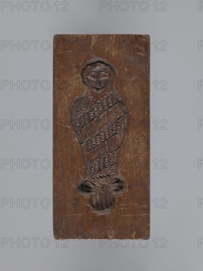 Double-sided gingerbread form. Side A: female figure; Side B: baby in swaddling clothes. Maker unknown woodcarver or gingerbread maker. Gingerbread mold, decorative/applied folk art from Silesia Province of Silesia, 1742–1918. Rectangular form: one side shows a standing female figure wearing a headscarf, leaning on a ladder and holding a broom; the other side shows a baby in swaddling clothes decorated with a geometric ornament. On one edge the date 1830 is engraved with the letter S against an anchor background and, below it, the letter M mark of the maker. Date: 1830. Dimensions: height 13.5 cm, width 6.5 cm, depth 4.5 cm. Tags: gingerbread, decorative art, applied art, folk motifs, female figures, children, babies, customs, souvenirs., A rectangular wooden panel with a carved figure in relief, showing a head with facial features and hair and a body wrapped in a patterned textile or banding, finishing in a stylized carved element at the base; the wood shows a warm brown tone with dar...