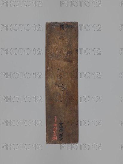 Double-sided gingerbread mould with the image of a rider on both sides, woodcarver or gingerbread maker. Rectangular wooden mold featuring on one side a rider-trumpeter in a tricorn hat wearing a 17th–18th-century costume long caftan, breeches, long boots seated on a horse with decorative tack; the rider and horse stand on a base decorated with plant and geometric ornament. Reverse side shows another rider probably a hussar seated on a horse, wearing a high mirliton cap and a fur-lined jacket, with geometric and floral ornament at the bottom. One edge engraved with the date 1797 and, centered in the date, the letter S over an anchor maker's mark. Gingerbread mould, applied/decorative folk-style motifs; Province of Silesia, 1797. Dimensions: height 19 cm, width 15 cm, depth 5.5 cm., A vertical rectangular wooden object with a worn, smooth surface and rounded top and bottom edges resting against a plain light gray background, showing a range of brown tones from light to dark with darker ...