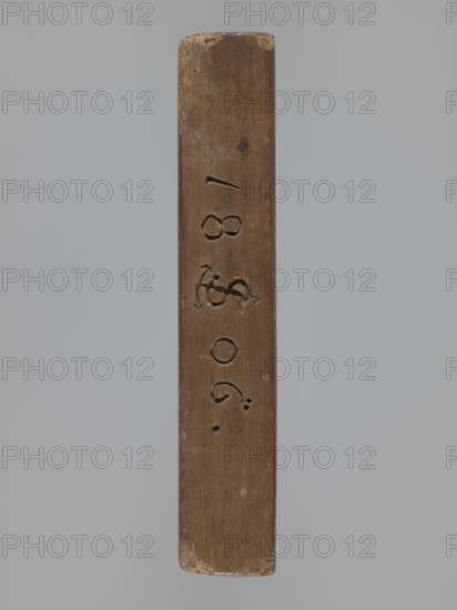 Double-sided gingerbread mould. Obverse: board with letters of the alphabet carved on it. Reverse: image of a running wild boar across a meadow. Double-sided rectangular mould; on one edge a date engraved: 1806, with the letter S on the background of an anchor mark of the woodcarver or gingerbread maker. Materials/subject: animals, gingerbread, folk-style decorations, wild boar iconographic, alphabet, folk motifs. Date: 1806. Place/region: Province of Silesia 1742–1918. Type: form. Dimensions: height 16 cm, width 12 cm, depth 3 cm., A vertical rectangular wooden object with a worn surface and rounded short ends, showing carved indentations and small gouges along its length; the wood is predominantly brown with lighter worn spots and a few darker marks, set against a plain light gray background.