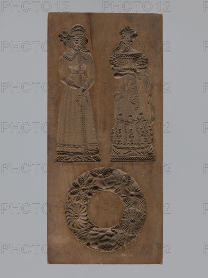 Double-sided gingerbread mould. Obverse: two female figures and a wreath; Reverse: two male figures and a house with a windmill. Woodcarving, folk-style decoration; genre scenes, houses, wreaths, windmills, peasants, gingerbread mould. Rectangular form; one side: at top two female figures in mid-19th-century costumes—one in an elegant dress with a bonnet decorated with flowers, the other in a richly flowered folk dress—and at the bottom a wreath woven of flowers and leaves. Other side: upper part shows two male figures in peasant costume left figure leaning on a shovel, right figure likely a sower; bottom shows a decorative motif of a house among meadows and trees with a windmill beside it. 18th–19th century, Province of Silesia 1742–1918. Height 28.5 cm, width 13 cm, depth 3.6 cm., A rectangular wooden panel with carved reliefs showing two standing female figures in long dresses and ornate hats above a circular wreath-like floral carving; the wood appears brown with areas of lighter a...