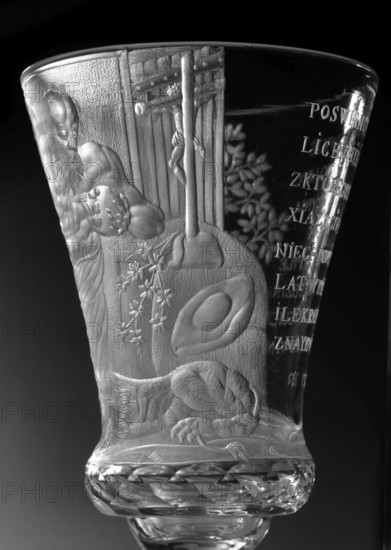 Chalice, glass, 1736–1744. Naliboki, Belarus Grand Duchy of Lithuania. Height 17.2 cm; width 7.7 cm. Round foot, slightly raised, trace of adhesive; baluster stem, solid, faceted, separated from the foot by two plates with a ring, one of them with a flower; separated from the bowl by two plates of different diameter and a knob. Conical bowl, twice puffed out at the base, cut into rows of lenses. Engraved, biaxial decoration covering the entire bowl: seated Saint Jerome holding a skull, a lion at his feet, in a room with bookcases and a side table; inscribed panel reading translated THE LORD'S GIFT OF HIS LIFE / FROM WHICH HE MAKES / THE PRINCE OF SACRIFICES / MAY THE HOUR Strike for so many prosperous years / HOW MANY DROPS IN THE GOBLET / WHAT WINE IS IN THE WINE. Wide geometric-patterned band on the foot. Attributed maker: Naliboki glassworks 1722–1862. Associated names: Hieronim Florian Radziwill 1715–1760; Radziwill family; skull anatomist. Function: vessel, chalice., The image sho...