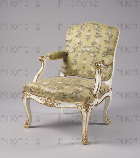 Armchair, Rococo style, floral decoration, cabriole legs, silk fabrics, patterned floral fabrics, upholstered seat, backrest, armrests, carved, white-lacquered and gilded. Cabriole legs, arched into the frame, cut out in a wave-like manner at the bottom; trapezoidal seat with a slightly bulging front frame. Disc-shaped backrest, nearly square, topped with an arch, with slightly concave side rails, straight in line with the sitter's back, slightly tilted with a clearance. Armrests end in a volute, on recessed, slightly S-shaped supports. Edges of all frame elements highlighted with a gilded half-cylinder. Central part of the front frame and upper part of the front legs feature carved floral decorations; ends of the armrests and the feet feature gilded acanthus leaves. Entire piece reupholstered with cream-colored silk fabric satin-weave ground, accented with colored silk and brocaded twill weave with silver thread; decorated with wreaths and alternating vertical garlands, with small flo...