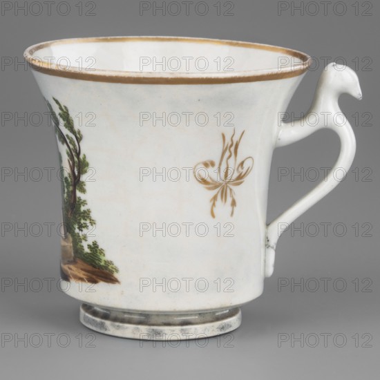 Cup, Korzec Porcelain and Faience Manufactory; 1790–1832 forgery. Cup from a service, chalice-shaped with a stepped foot and a curved handle ending in a bird's head. White with a greyish hue, painted polychromatically and gilded. Front: romantic landscape with ruins and trees and two boulders—the larger inscribed Zaslaw, the smaller dated 1792—topped by a statue of a standing man. Reverse: slender tree with two branches, shrubs and mosses below. On either side of the handle, a gold-painted flower with stylized petals. Painting dominated by light greens, ochres, and browns. Inscription and date indicate the site of the victorious Battle of Miropol during the Polish–Russian War following the adoption of the Constitution of May 3rd. Dated 1800–1815. Place of manufacture: Korzec, Volhynian Governorate Poland. Vessel; height 7.0 cm, width 8.5 cm, depth 7.0 cm., A white porcelain cup with a flared rim and a rounded base sits against a gray background, featuring a small painted scene of a tre...