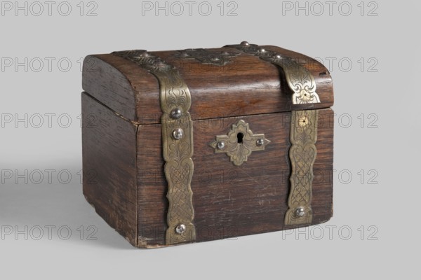 Box, Cuboid storage box 1840–1860, Central Europe with rounded edges on the long sides of the lid, veneered with rosewood. Fitted with engraved brass ribbons with cut-out edges forming strap hinges. At the top of the front wall of the body is a lock plate cut from brass sheet in a shape similar to a cross; a similar plaque is centered on the lid. Appliqués attached with spherical-head pins. Lid lined with glass on the inside. Mortice lock with one striker mounted in the lower rim of the lid. Plant decoration; geometric ornament. Height 12.6 cm, width 14.8 cm, depth 12 cm., A small wooden chest with a rounded lid sits against a light gray background; the chest is dark brown with visible wood grain and worn edges, and it features decorative metal straps and fittings in a brass tone with engraved patterns and a few silver-toned round rivets.