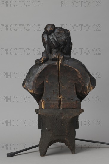Bed finial from the Hospital of St. John of God in Warsaw, Fontana, Jakub 1710–1773 designer; co-creator, Redler, Jan Chryzostom 1704–1779 woodcarver; author; female busts; Hospital of St. John of God Warsaw; 1650–1944; Hospitallers of St. John of God order; Czartoryski, August Aleksander 1697–1782; baroque style. HOSPITAL BED FINIAL in the form of a pediment with volutes on the sides and a corbel in the middle supporting the bust of a young woman; fastened with two pins to the front section of the cornice crowning the canopy. The outline of the finial and the corbel are highlighted with a black ribbon stucco inlay. The corbel has an oval opening filled with a wooden, rotating medallion with inlaid letters on the obverse and reverse missing. The runners feature garlands made of ribbons and bay leaves; the volutes feature small brackets with turned, cup-shaped pinnacles. ca. 1757–1760, Warsaw; furniture fragment. Height 66 cm, width 93 cm, depth 16 cm., A carved wooden bust shown from t...