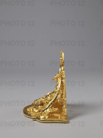 Hanging console, acanthus ornament, floral ornament, Rococo style, ca. mid-18th century, Central Europe, piece of furniture, height 37.3 cm, width 41.5 cm, depth 26 cm, A decorative metallic object with a shiny gold finish sits against a smooth gray background; the object has an ornate, curving profile with sculpted floral and leaf motifs, a rounded base with raised decorative elements, and a vertical back panel with matching ornamental detailing, all rendered in gold with highlights and shadows from the lighting, while the background appears uniform gray.
