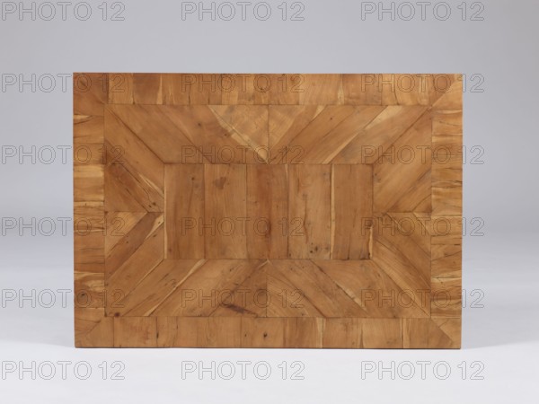 Table, snakes, rosettes ornament, plant decoration, classicism style, rectangular table with a drawer in a fluted frame, supported by four straight, angular, tapering legs terminating in wedge-shaped feet. Entire piece veneered with rosewood and polished. The tabletop has a straight, plate-shaped rim, veneered in a cross pattern, with a rectangular central field and a narrow cross-frame, blintzed on the underside. Drawer handle in the form of a knob made of twisted rope with rosette plates. The drawers form a glued frame with sockets in the corners for mounting the leg tenons. Late 18th century, possibly Warsaw; furniture, table; height 76.5 cm, width 84.2 cm, depth 59.5 cm., A rectangular wooden surface with a parquet pattern made of several wooden planks arranged in concentric rectangular bands, showing wood grain, knots, and natural blemishes; the wood appears in warm brown and tan tones with variations of lighter beige and darker brown; the background is a smooth pale gray transiti...