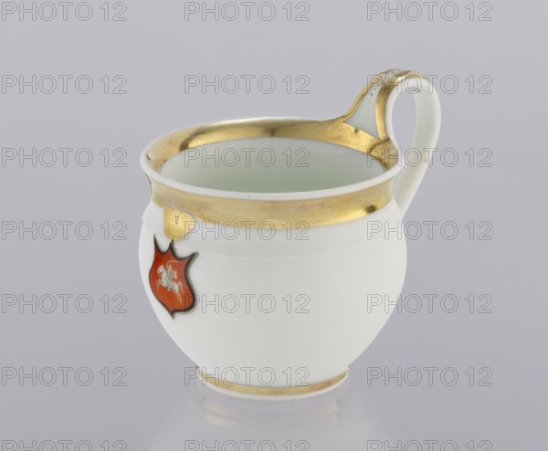 Cup with the Pogon coat of arms, Korzec Porcelain and Faience Manufactory; 1790–1832. Campana-type porcelain cup, hemispherical with a high loop handle. On the front, on a red coat of arms with a black border, the Sanguszko family coat of arms Pogon topped with a gilded bipartite closed crown. Edges, top of the handle, and rim around the base gilded. 1829, Poland. Vessel. Height 7.5 cm; width 9.0 cm; depth 7.2 cm., A white porcelain cup with a rounded body and a curved handle, featuring a band of gold around the rim and a thin gold line near the base; the inside of the cup appears pale green. There is a small red shield-shaped decoration on the side with a gold heart-shaped accent above it, and the handle has gold detailing. The background is a soft light gray.