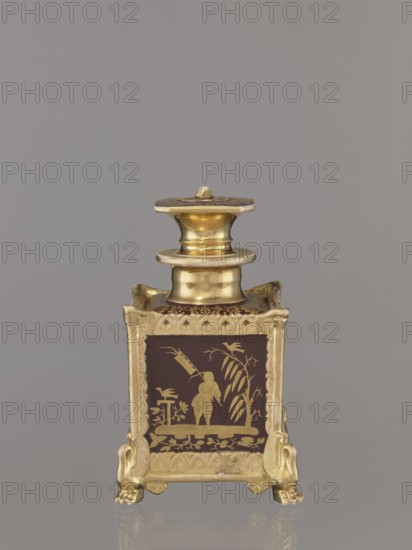Bottle with lid, porcelain factory Gardner, Francis 1766–1917. Cubic bottle with profiled short neck and square stopper. Plastic ornamentation on the edges; swan-shaped feet in late Empire style one paw fragment missing. Gold-painted decoration with four genre scenes of Chinese people on the four sides; floral ornament on the top of the bottle and stopper; gilding abrasions. Chinoiserie. c. 1840, Russia, Wierbilki. Vessel. Height 18.5 cm, width 11.2 cm., A small ornamental container with a square body and a lid, finished in metallic gold and deep brown; the lid and neck are shiny gold with rounded and flared shapes, and the body has deep brown panels decorated with gold silhouette scenes showing a standing figure, plants, and birds; the square body sits on ornate gold feet shaped like stylized animal paws, and the edges and top rim have raised gold decorative borders; visible colors include gold and deep brown against a neutral gray background.