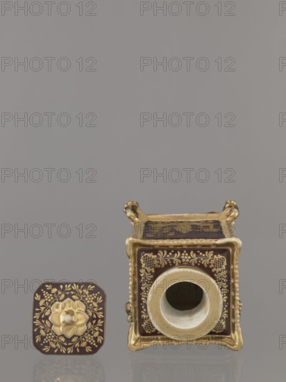Bottle with lid. Porcelain, Gardner manufactory Francis Gardner; established 1766–1917. Cubic bottle with a profiled short neck and square stopper. Plastic ornamentation on the edges, swan-shaped feet in late Empire style one paw fragment missing. Gold-painted decoration: four genre scenes with Chinese figures on the four sides. Floral ornament on top of bottle and stopper; gilding abrasions. Circa 1840, Russia, Wierbilki. Vessel. Height 18.5 cm; width 11.2 cm., The image shows a decorative square container and its detached lid resting on a reflective surface against a plain gray background. The container is ornate with a glossy dark brown base color and extensive gold ornamentation along its edges and panels; the front has a circular opening rimmed in an off-white or cream color. The lid, positioned to the left of the container, shares the dark brown and gold floral motifs and features a raised gold floral knob at its center. The gold detailing includes delicate vines and floral patte...