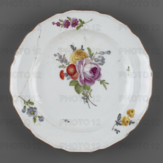 Shallow plate, Churfuerstliche Porcellain Fabrique, Meissen 1763/74–1814, Marcolini period 1774–1814; soft-paste porcelain. Shallow plate with a 12-leaf collar with a wavy edge and an ochre border. In the central mirror: a bouquet with a raspberry rose, blue bellflowers and brick-red daisies . On the collar: three floral sprays, including yellow roses; leaf projections. At the bottom: a black overglaze mark SAR./K., dated 1774–1814, Meissen, Saxony, Germany. Makers/attribution: Stanislaw August Poniatowski King of Poland; 1732–1798 noted in association with the piece. Function: vessel plate., A white ceramic plate with a scalloped rim and a narrow brown edge, decorated with a painted floral bouquet at the center featuring a large purple-pink rose, a yellow bloom, red-orange flowers, green leaves, and small gray and purple accents, with several smaller floral motifs around the rim including purple-pink, gray-blue, and yellow flowers; the plate shows a visible crack and some surface disc...