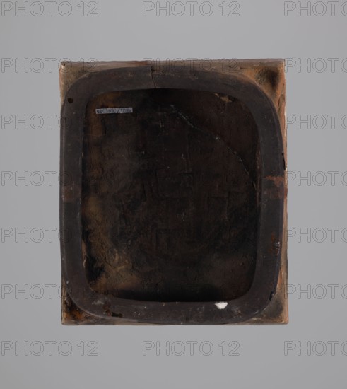 Tile, tiles, Hutsulshchyna, stoves, saints, dates, with a representation of a saint, 1851, Hutsulshchyna, tile, height 23.7 cm, width 20.0 cm, depth 6.0 cm, A square object viewed from above with a recessed, rounded-rectangular central cavity; the outer surface shows tones of brown and tan with areas of darker brown and black, while the interior of the cavity is predominantly dark brown to nearly black with some lighter brown patches and a small white mark on the inner rim; the rim itself is a darker brown and appears worn with rough texture and subtle cracks; the background is a uniform light gray.
