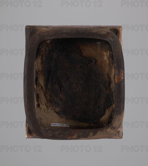 Tile, tiles, birds, stoves, plant decorations, Hutsul region, decoration with a rooster motif, 19th century, tile, height 20 cm, width 23 cm, depth 6 cm, A square, shallow container viewed from above with rounded inner edges and a rough, uneven interior surface. The rim and outer surface show dark brown and reddish-brown tones with areas of lighter brown and small patches of orange. The interior has a central dark area of deep brown to almost black with surrounding mottled brown and tan textures. The background is a flat light gray.