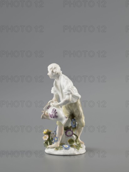 Gardener, Koenigliche Porzellain Fabrique, Meissen 1710–1763 manufacturer, Kaendler, Johann Joachim 1706–1775 sculptor, Reinicke, Peter 1715–1768 sculptor, gardeners, figurines. On a circular base with a high tree trunk and plastic tufts of flowers stands a slightly bent barefoot man, leaning against the trunk, in knee-length trousers and a luxurious shirt with rolled-up sleeves; he holds a watering can in his left hand, tilting it to water the flowers, and supports the spout with a strainer in the palm of his other hand. ca. 1760, Meissen, Saxony, Germany. Porcelain figurine, height 12 cm., A porcelain figurine of a person standing on a rounded base, rendered in white with painted details; the figure wears a white upper garment and pale yellowish-beige trousers, and is leaning forward while holding a white watering vessel decorated with purple floral motifs; the base and surrounding area feature a group of small flowers and leaves in blue, yellow, purple, pink, green, and white; the b...