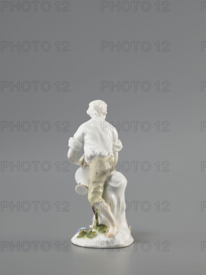 Gardener, Koenigliche Porzellain Fabrique, Meissen 1710–1763; Kaendler, Johann Joachim 1706–1775 sculptor? ; Reinicke, Peter 1715–1768 sculptor?; gardeners, figurine. On a circular base with a high tree trunk and plastic tufts of flowers stands a slightly bent barefoot man, leaning against the trunk, in knee-length trousers and a luxurious shirt with rolled-up sleeves; he holds a watering can in his left hand, tilting it to water the flowers, and supports the spout with a strainer in the palm of his other hand. Ca. 1760. Meissen, Saxony, Germany. Porcelain figurine, height 12 cm., The image shows a porcelain figurine photographed from behind against a gray background; the figurine depicts a person with light-colored hair wearing a white shirt and pale yellowish trousers, standing with one leg bent and one foot bare on a white base that includes green and blue painted foliage and a small purple detail, and a white draped form beside the figure.