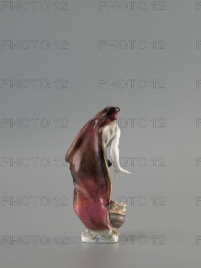 Winter — Allegory. Koenigliche Porzellain Fabrique, Meissen 1710–1763. Seasons allegory: Winter. Figurine in black, mid-18th century, Meissen, Saxony. On a flat, quadrangular pedestal stands an old naked, barefoot bearded man in contrapposto, covered with a fur-lined cloak, a horn thrown over his head and flowing down his back, held by its other end in his left hand at hip level. He leans slightly and warms his right hand over a cauldron with a flame at his feet. Height 11.5 cm., A small glazed ceramic figure standing on a rectangular base with a draped cloak in shades of deep red, burgundy, and pink that transitions into darker brownish tones, revealed partially over a pale creamy white arm and hand extending outward; the cloak has glossy highlights and subtle darker speckling, and the base and exposed lower parts show off-white and light beige with a small area of muted blue; near the figure’s feet there is a rounded vessel in brown and beige with pale cream accents.