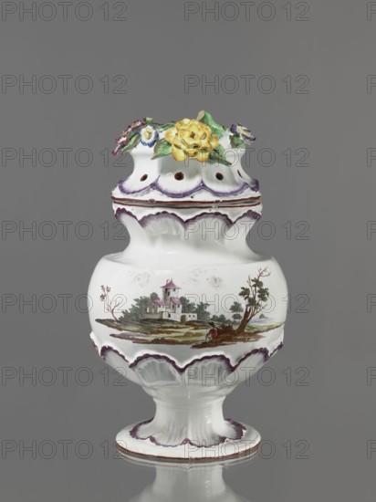 Pot-pourri vase with lid by Johann Georg Buchwald Cologne; 1769–1771. Porcelain pot-pourri vase with hemispherical body slightly closing at the top, almost flat shoulders, and a wide neck that slopes obliquely. Low stem widening into a round, wide foot. The neck, base of the belly, and foot are enclosed in a wreath of plastic shell ornament painted in purple. On the body are two landscapes with buildings against a background of trees. Hat-like cover with a brim enclosed in a shell ornament; on the top a plastic decoration of colorful flowers with a floral handle. Dated 1769–1771. Germany, Cologne. Vessel. Height 37 cm, width 26 cm., A white ceramic vase with a rounded body, narrow neck, and flared foot, featuring scalloped molded edges highlighted in purple and brown; the central body displays a painted rural scene with a small building and surrounding trees in greens, browns, and muted pinks, and a figure near the shoreline. The top rim is decorated with three-dimensional ceramic flow...