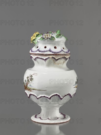 Pot-pourri vase with lid by Johann Georg Buchwald Cologne; 1769–1771. Pot-pourri vase with hemispherical body slightly closing at the top, almost flat shoulders, and a wide neck that slopes obliquely. Low stem widening into a round, wide foot. The neck, base of the belly, and foot are enclosed in a wreath of plastic shell ornament painted in purple. On the body are two landscapes with buildings against a background of trees. Hat-like cover with a brim enclosed in a shell ornament; on the top a plastic decoration of colorful flowers with a floral handle. 1769–1771. Germany, Cologne. Earthenware vessel; height 37 cm, width 26 cm., A white ceramic vessel with a rounded body, flared base, and a domed lid topped with sculpted flowers and leaves in green, yellow, and purple; the rim and scalloped edges are accented with a purple wash and thin brown lines, and there are painted landscape motifs with trees in brown and green on the body, all set against a plain gray background.