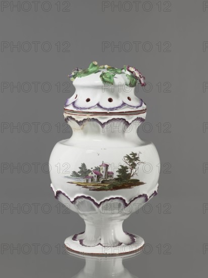 Pot-pourri vase with lid by Johann Georg Buchwald Cologne; 1769–1771. Porcelain pot-pourri vase with hemispherical body slightly closing at the top, almost flat shoulders, and a wide neck that slopes obliquely. Low stem widening into a round, wide foot. Neck, base of the belly, and foot enclosed in a wreath of plastic shell ornament painted purple. Two landscapes with buildings against a background of trees on the body. Hat-like cover with a brim enclosed in a shell ornament; top features a plastic decoration of colorful flowers with a floral handle. Dated 1769–1771. Germany, Cologne. Vessel; height 37 cm, width 26 cm., A white ceramic vessel with a rounded body, pedestal base, and a domed lid decorated with sculpted green leaves and small purple and pink flowers; the vessel features scalloped edges highlighted in purple along the top, middle, and base, and a painted landscape scene on the body showing a small building with a tower, surrounding trees, and ground in green and brown tone...