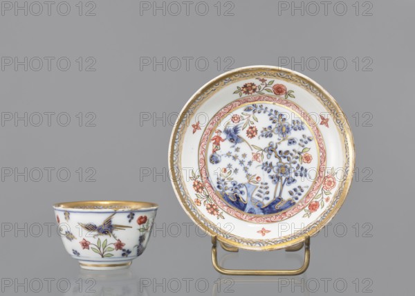 Bowl, house painter co-creator; Ferner, JF ca. 1750 or workshop co-creator; Königliche Porzellain Fabrique, Meissen 1710–1763 author. Hemispherical bowl with a rim at the bottom, parted, with a slightly rolled-up edge. Painted in cobalt in a Far Eastern motif with a bird and a rock by Fels und Vogel and with colorful house-painting decoration inside: a reclining man leaning against a rock, two floral compositions and an architectural motif in the circle of the bottom, around a cobalt branch. Floral decoration with a bird and a rock, cobalt semicircle pattern around the edge, flower in the bottom and gilded bottom rim. Mid-18th century; Meissen, Saxony, Germany. Porcelain vessel. Height 4.5 cm; diameter 7.8 cm., A small porcelain cup and a matching saucer sit against a gray background; the cup is white with hand-painted floral and bird motifs in blue, red, green, and gold, and a gold rim, while the saucer is white with an ornate central scene of blue floral branches surrounded by red an...