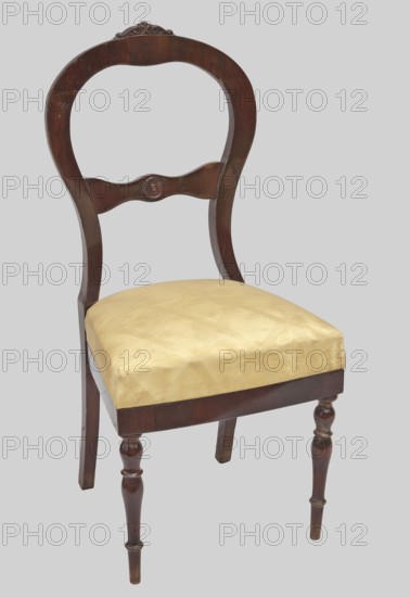 Chair, plant decoration, knobs ornament, Biedermeier and Louis Philippe styles, mahogany. Chair with a trapezoidal upholstered seat removable cushion and a balloon-shaped openwork backrest fastened in the middle with a decorative crossbar with a wavy outline. The front legs are turned and profiled; the rear legs are angular and arched backwards. The top is carved with acanthus leaves, and the center of the backrest crossbar has a decorative knob. Date: 1835–1845. Place of origin: Warsaw . Piece of furniture, seating furniture. Dimensions: height 105 cm, width 48.5 cm, depth 49.5 cm., A wooden chair with a dark brown curved back and carved decorative crest, a curved central back rail with a round carved detail, a padded seat upholstered in pale yellow fabric, turned front legs and plain rear legs, all set against a light gray background with visible wood grain and subtle wear on the finish.