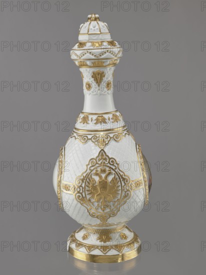 Bottle-shaped vase with a domed lid. Embossed and colorfully painted decoration. Four medallions set against a rococo latticework – a miniature portrait of Tsar Alexander II in ceremonial military uniform with epaulettes and a blue ribbon, the Tsar's monogram, and the Tsar's double-headed eagle on the other two. Gilded floral and plant elements. A gap at the base, worn gilding. Made 1869, St. Petersburg, Russia. Porcelain vessel, height 49.5 cm, width 22 cm. Modeller: August Karlowicz 1817–1904. Manufacturer: Imperial Porcelain Factory in St. Petersburg 1744–1917., A decorative ceramic vessel with an elongated, bulbous body and a tall neck topped by a domed lid sits against a plain gray background; the vessel is primarily white with ornate gold accents and raised decorative patterns, including scrollwork, floral motifs, and a framed heraldic double-headed eagle medallion on the body, a textured lattice pattern on the white surface, gilt bands and leaf-like ornamentation around the neck...